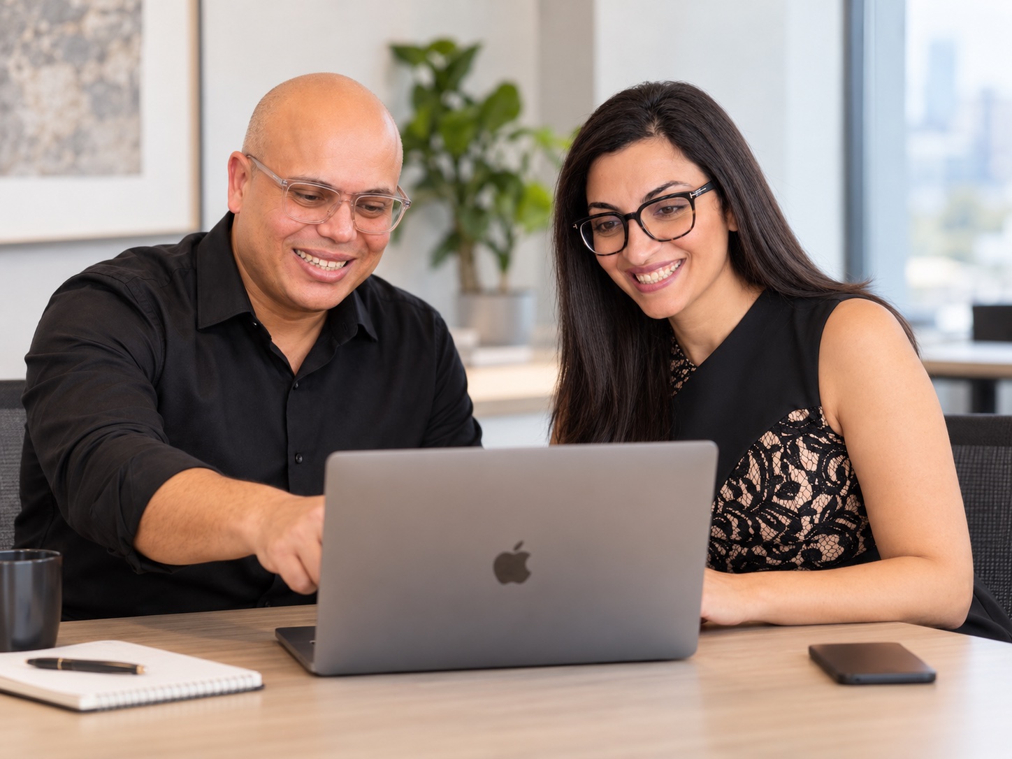 Two members of the WebNeuro team reviewing work on a laptop