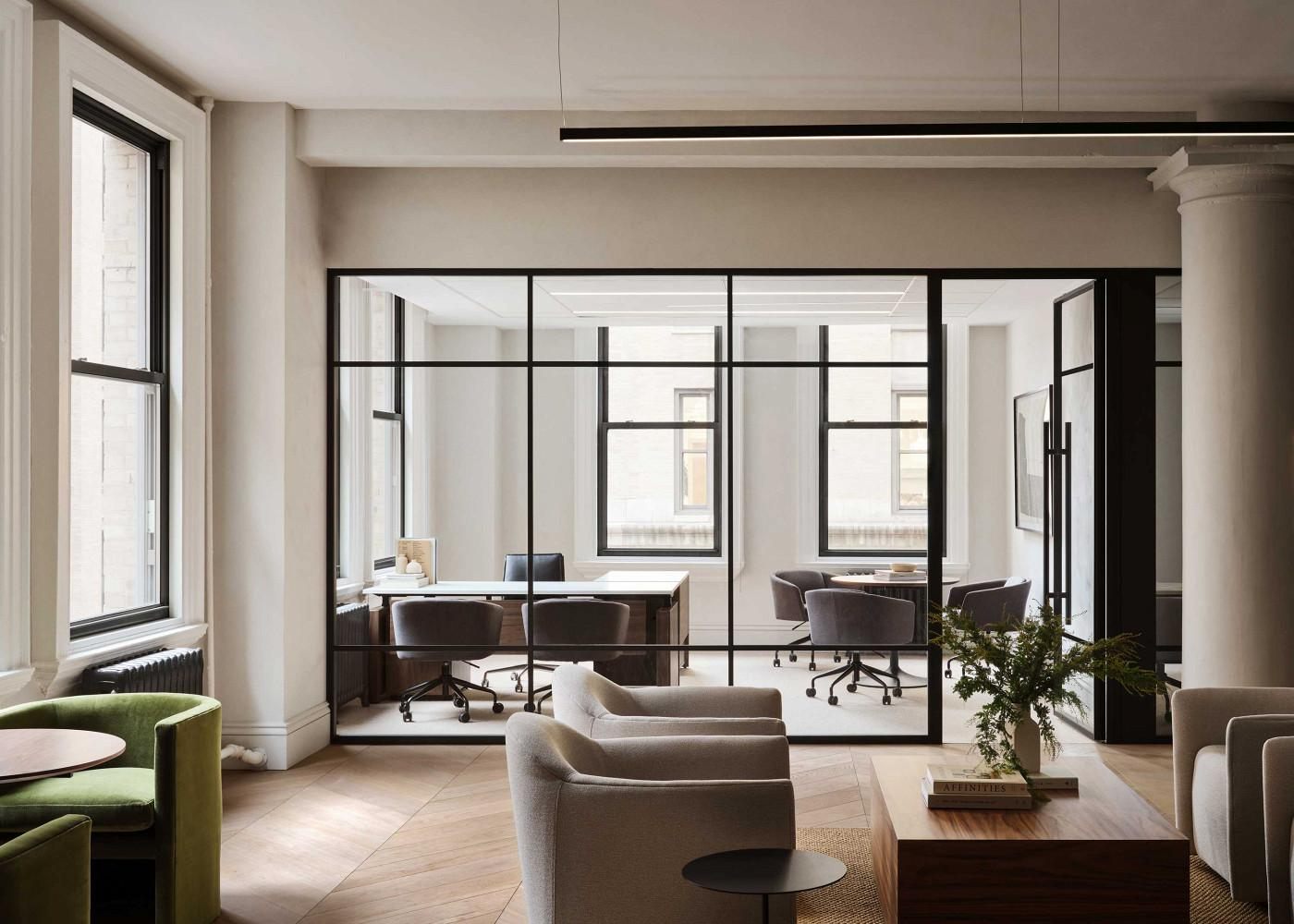 A calm office lounge with a glass-walled meeting room
